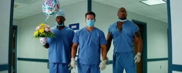 Anthony Mackie, Mark Wahlberg e Dwayne Johnson vestiti da medici in una scena di Suda e cresci