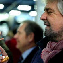 Tsunami Tour: Beppe Grillo guarda ammirato una statuetta che lo raffigura in una scena del documentario