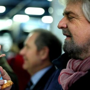 Tsunami Tour: Beppe Grillo guarda ammirato una statuetta che lo raffigura in una scena del documentario