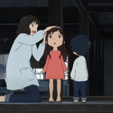 Wolf Children: la mamma misura i due piccoli bambini lupi a una trave della casa