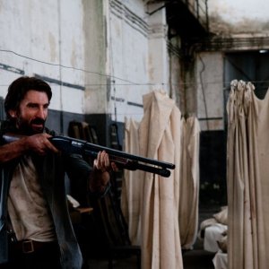 Open Grave: Sharlto Copley punta il suo fucile in una scena del film