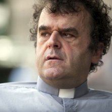 Un castello in Italia: Pippo Delbono nei panni del prete in una scena del film