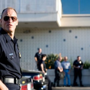 Il poliziotto Woody Harrelson appoggiato alla sua auto in Rampart