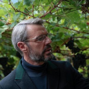 Vinodentro: Lambert Wilson intento a esaminare l'uva del vigneto