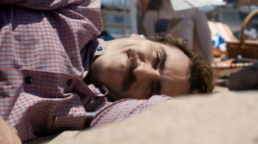 Lei: Joaquin Phoenix sdraiato sulla spiaggia in una scena del film