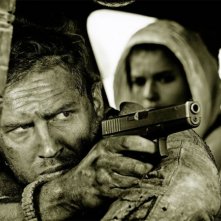 Mad Max: Fury Road - Un primo piano di Tom Hardy menytre impugna la pistola