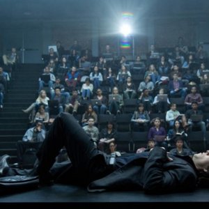 The Gambler: Mark Wahlberg sdraiato su una scrivania di fronte a una folla di studenti