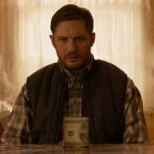 Chi è senza colpa: Tom Hardy davanti a un rotolo di dollari
