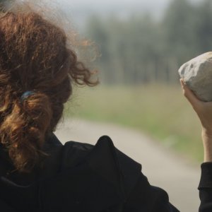 N-Capace: Eleonora Danco (di spalle) impugna una pietra in una scena del film