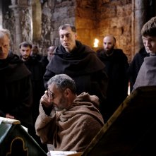 Il nome della rosa: Guglielmo, John Turturro, usa i suoi occhiali in biblioteca