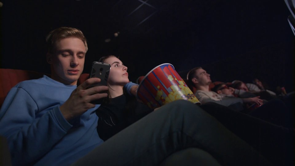 Videoblocks Young Man Using Smartphone In Movie Theatre Young Man Using Phone In Cinema Uncultured Manners In Movie Theater Rjotp57Ux Thumbnail 1080 01