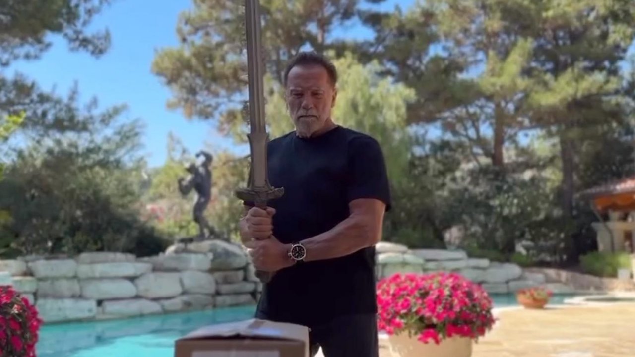 Arnold Schwarzenegger usa la spada di Conan il Barbaro per aprire le scatole del suo nuovo libro